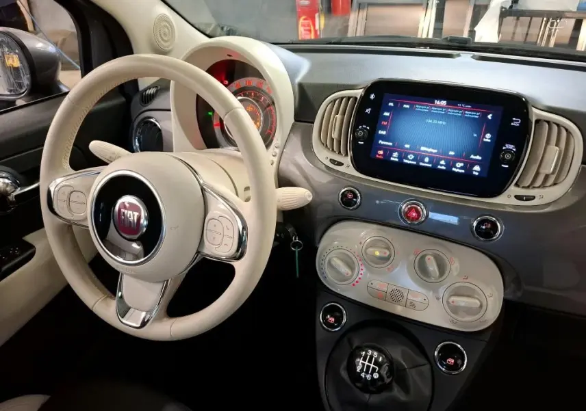 Vue intérieure côté conducteur de la Fiat 500 2022 Gris Electroclash, volant beige et tableau de bord avec écran tactile.