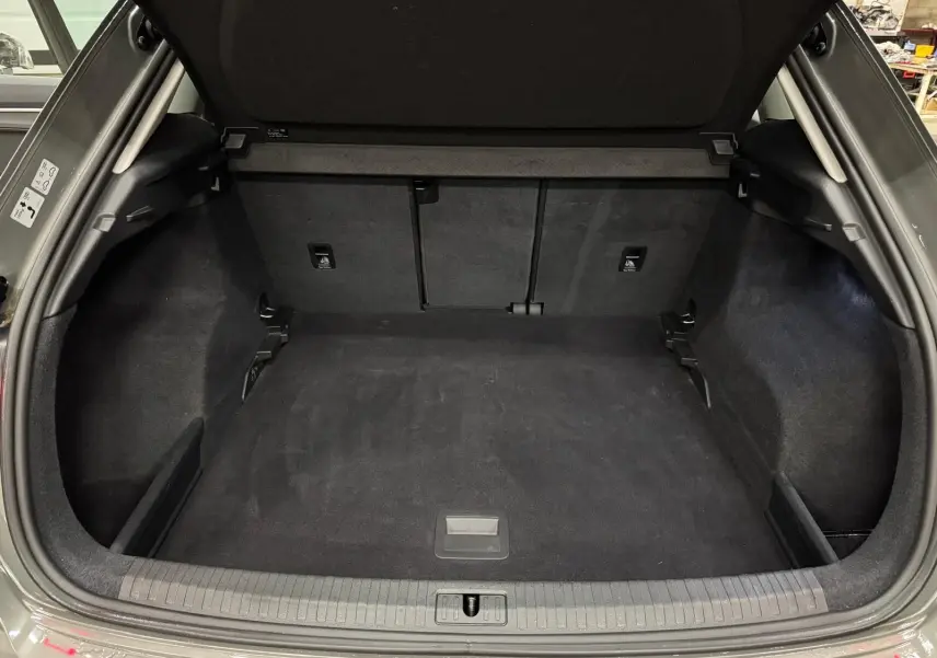 Coffre ouvert vu de l'arrière d'un Audi Q3 Business gris, montrant un espace de chargement propre et spacieux.