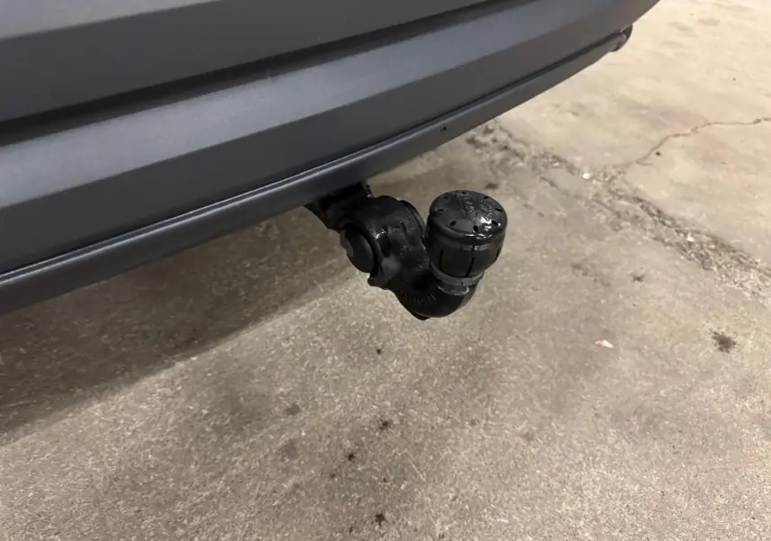 Gros plan sur l'attelage d'une Audi Q3 Business gris, visible sous le pare-chocs arrière dans un garage.