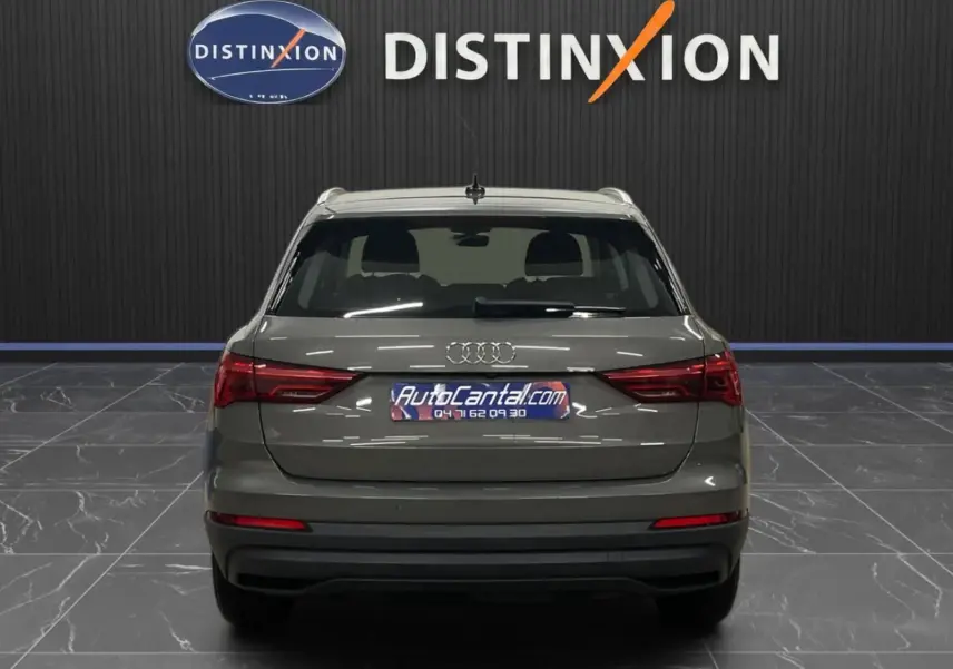 Vue arrière d’un Audi Q3 Business gris avec feux arrière LED dynamiques dans un showroom.