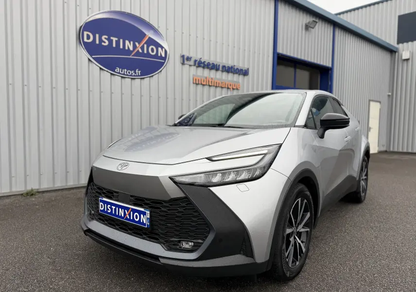 Toyota C-HR Hybride gris en 3/4 avant droit, avec calandre noire et phares LED fins visibles.