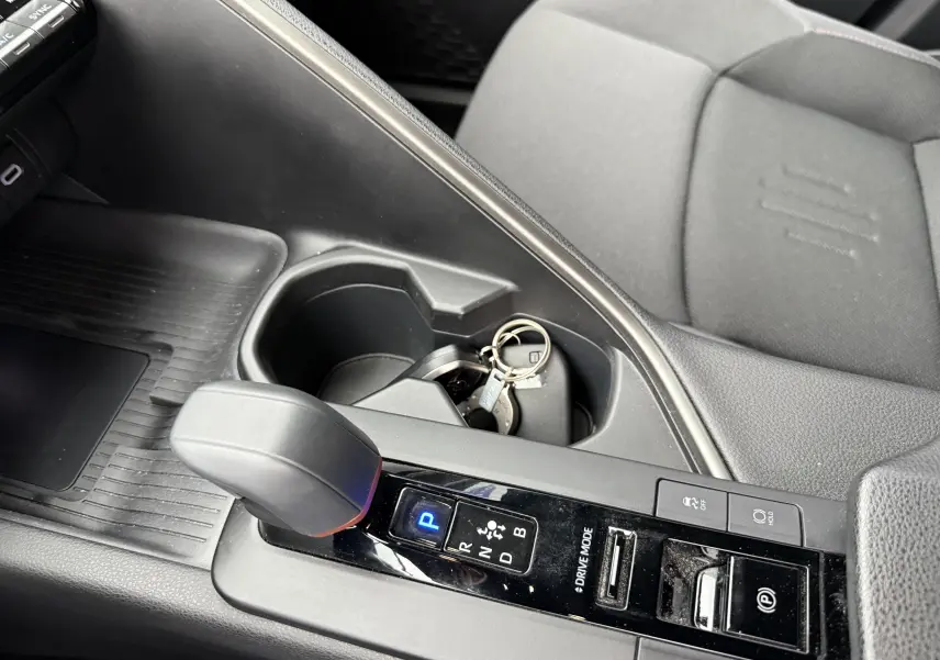 Vue rapprochée de la console centrale grise du Toyota C-HR Hybride 2024, avec levier de vitesse automatique et porte-clés.