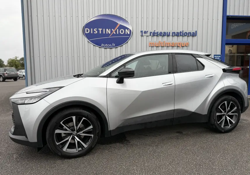 Vue de profil côté gauche du Toyota C-HR Hybride gris 2024 avec jantes bi-ton et lignes anguleuses marquées.