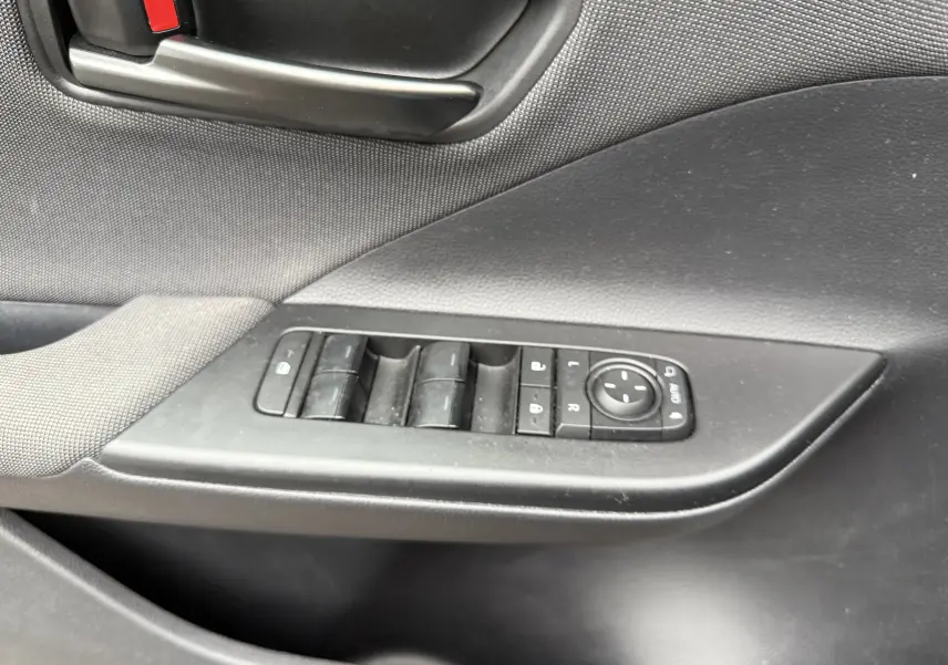 Gros plan sur la commande des vitres et le bouton de réglage des rétroviseurs côté conducteur du Toyota C-HR Hybride gris 2024.