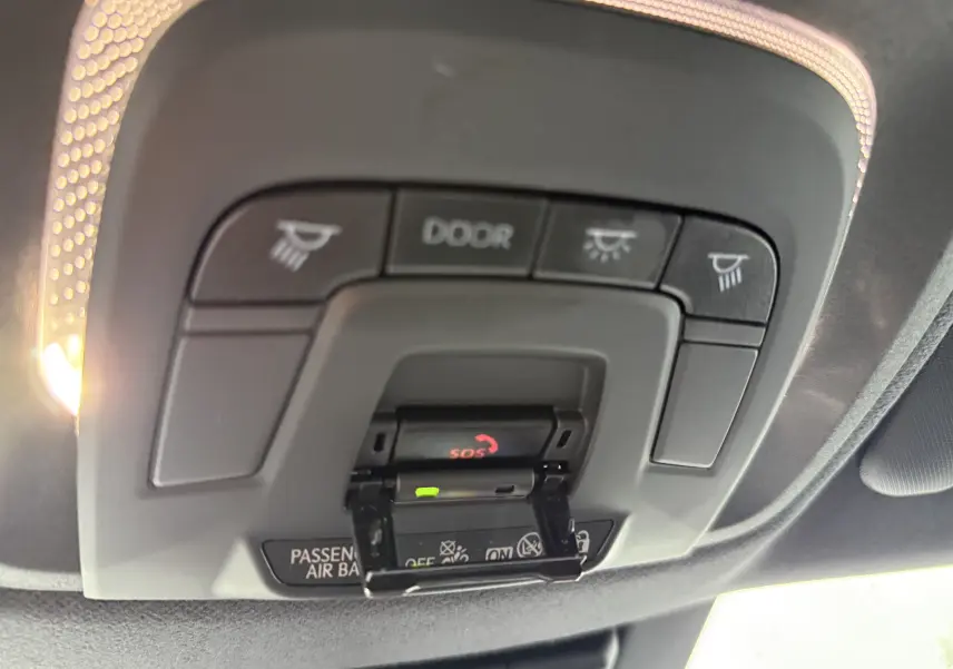Vue intérieure du plafonnier du Toyota C-HR hybride gris 2024, avec boutons d’éclairage et alerte SOS visible.