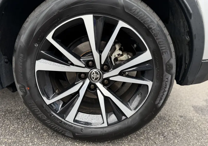 Gros plan sur la jante alliage bicolore noir et argent du Toyota C-HR Hybride gris, roue avant droite.