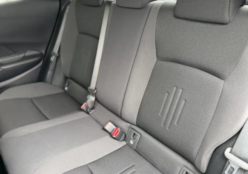 Vue rapprochée des sièges arrière gris du Toyota C-HR Hybride 2024, montrant les ceintures et les textures du tissu.