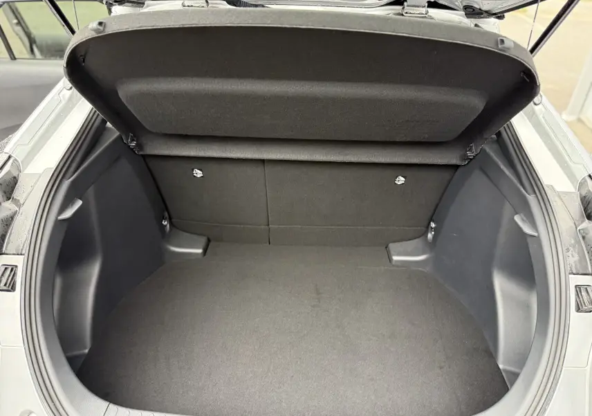 Coffre ouvert en vue plongeante du Toyota C-HR Hybride gris 2024, montrant un espace de chargement propre et spacieux.