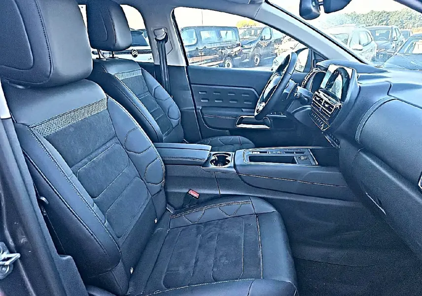 Vue intérieure côté conducteur du Citroën C5 Aircross 2024, sièges noirs en cuir et alcantara avec console centrale moderne.
