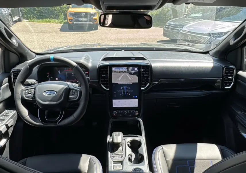 Vue intérieure avant du Ford Ranger gris carbone 2026, mettant en valeur le volant multifonctions et l'écran tactile central vertical.