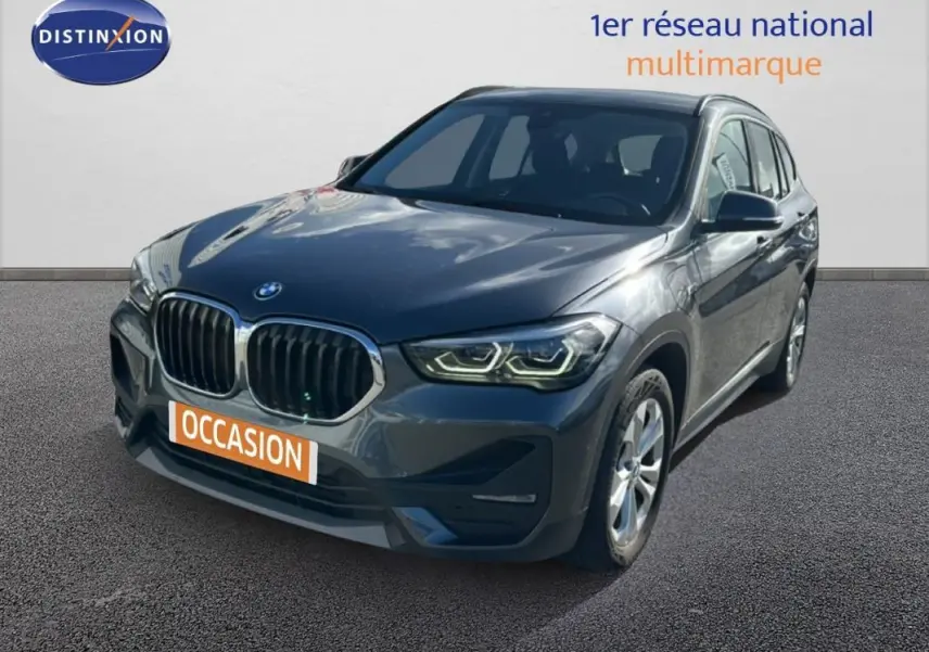 BMW X1 gris foncé vue 3/4 avant droit, avec calandre double haricot et phares LED allumés.
