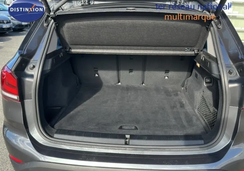 Coffre ouvert vu de l'arrière d'un BMW X1 gris foncé, montrant un espace de chargement propre et spacieux.