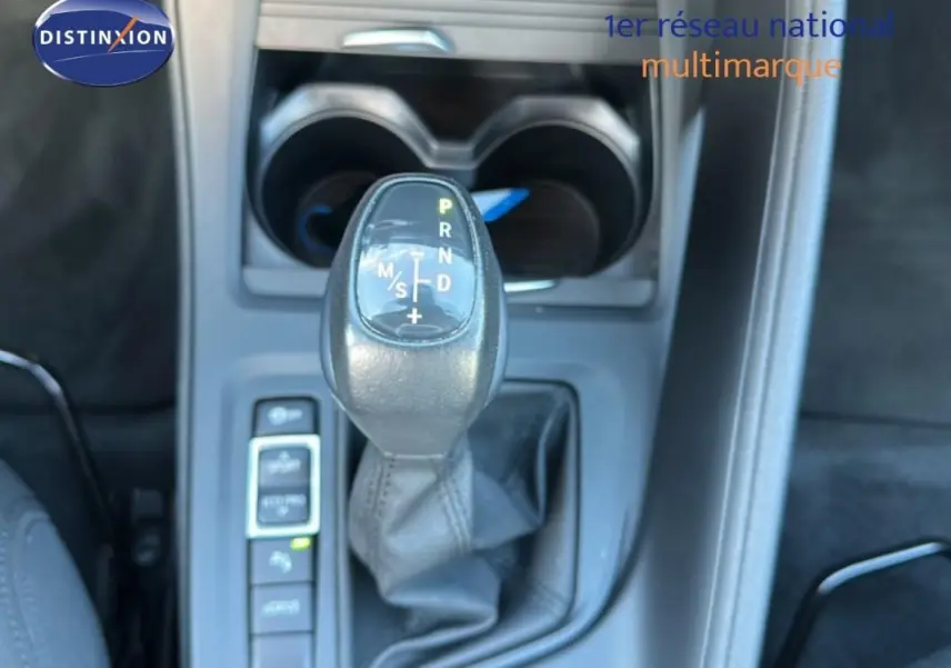 Gros plan sur le levier de vitesses automatique noir de la BMW X1 gris foncé, avec porte-gobelets en arrière-plan.