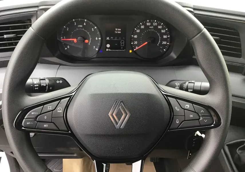 Vue rapprochée du volant noir de Renault Master blanc 2025 avec commandes intégrées et tableau de bord digital.