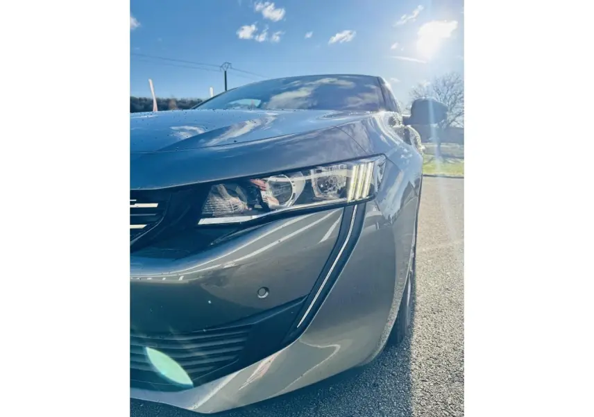 Gros plan sur l'avant droit gris amazonite d'une Peugeot 508 2019, mettant en valeur le phare et la calandre chromée.