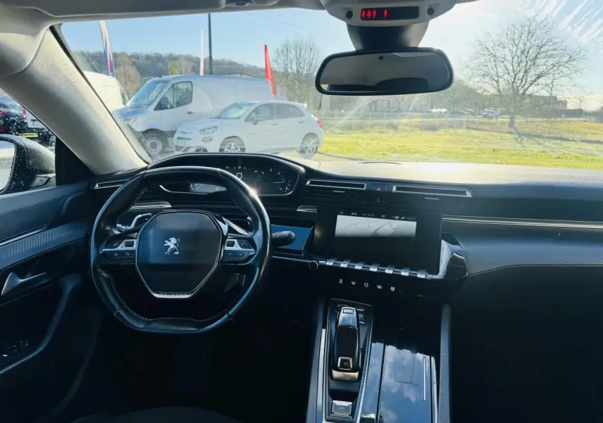 Vue intérieure avant de la Peugeot 508 gris amazonite, volant compact, écran tactile et planche de bord carbone.