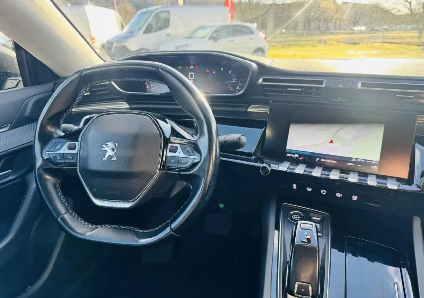 Vue intérieure avant de la Peugeot 508 gris amazonite, volant compact cuir et écran tactile avec navigation allumé.