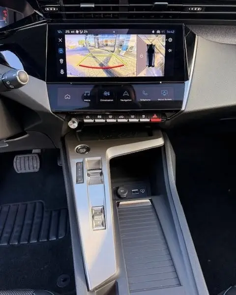 Vue intérieure du tableau de bord et console centrale de la Peugeot 308 Hybrid blanche, écran tactile avec caméra de recul affichée.