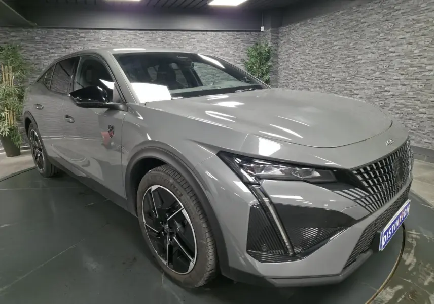 Vue 3/4 avant gauche de la Peugeot 408 gris métallisé avec calandre noire et jantes alliage 19 pouces diamantées.