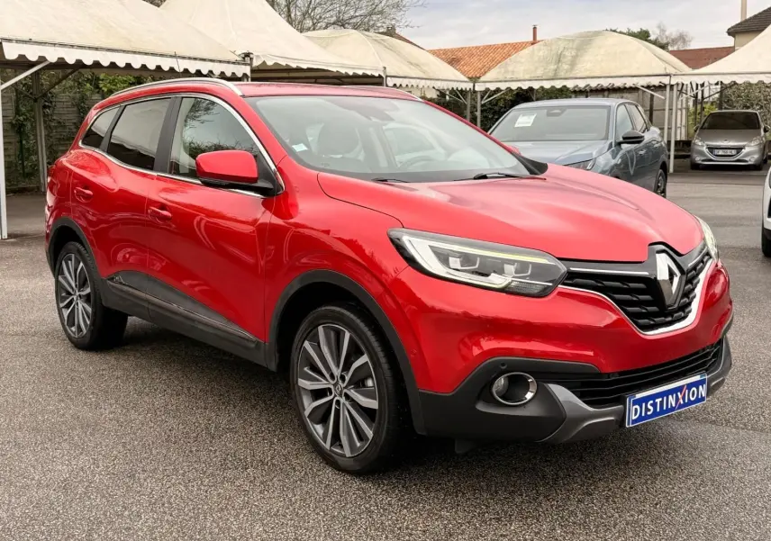 Renault Kadjar rouge flamme en 3/4 avant droit, mettant en valeur ses jantes bi-ton et ses optiques modernes.