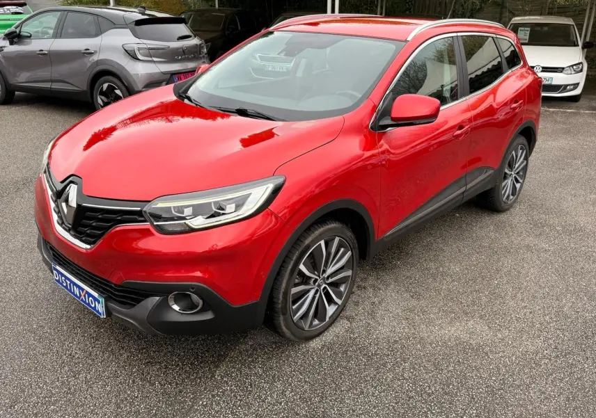 Vue 3/4 avant droit d’un Renault Kadjar rouge flamme avec jantes alliage bicolores et calandre noire distinctive.