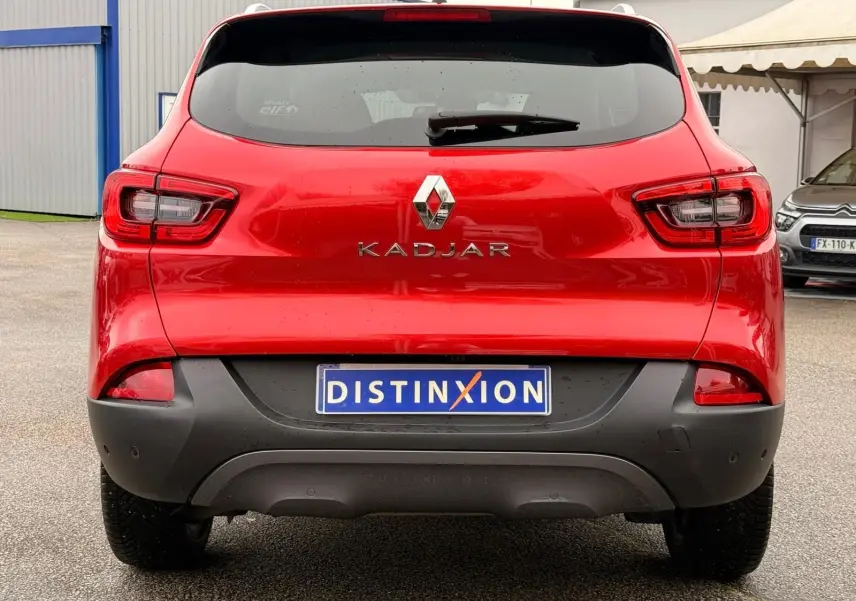 Vue arrière d'un Renault Kadjar rouge flamme de 2016 avec pare-chocs noir et plaque d'immatriculation Distinxion.