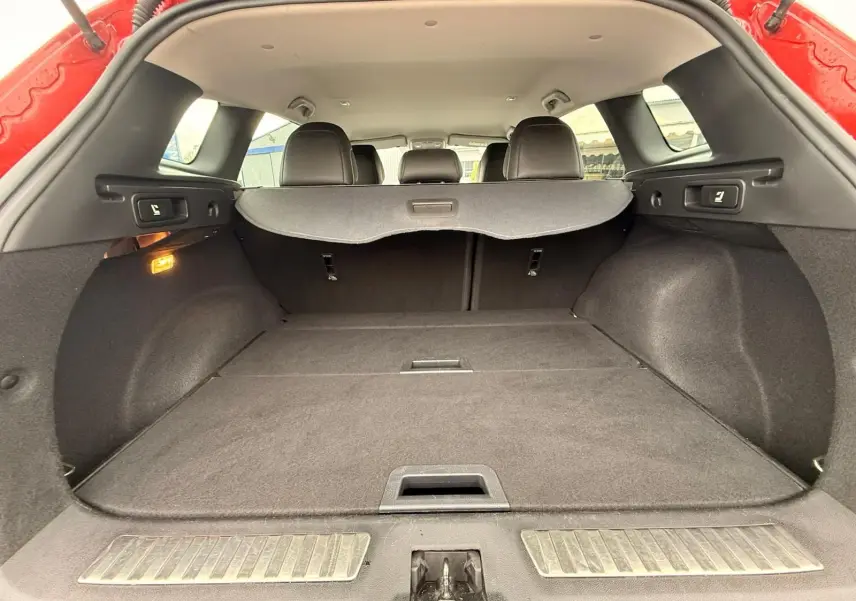 Vue intérieure du coffre ouvert du Renault Kadjar rouge flamme, montrant l'espace de chargement et la plage arrière.