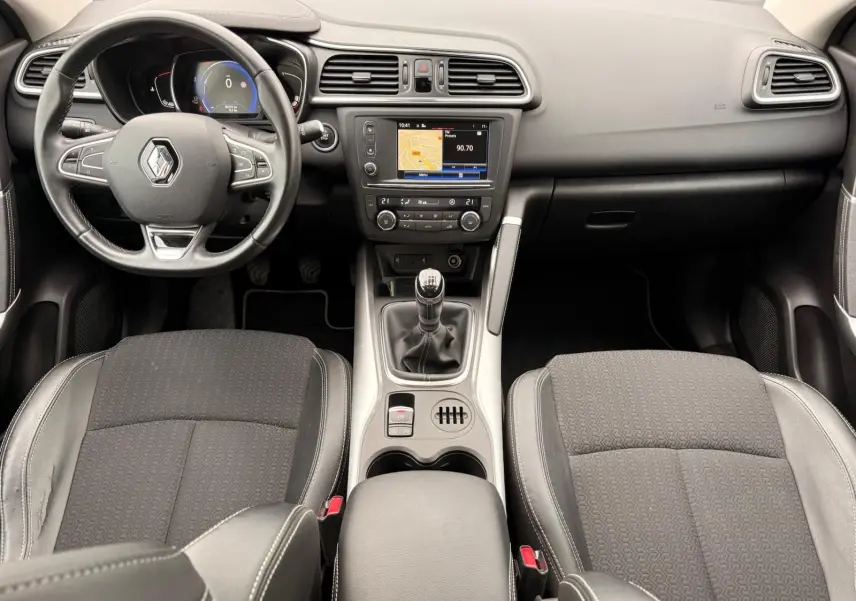 Vue intérieure avant du Renault Kadjar 2016, tableau de bord et volant en cuir noir avec console centrale et boîte manuelle.
