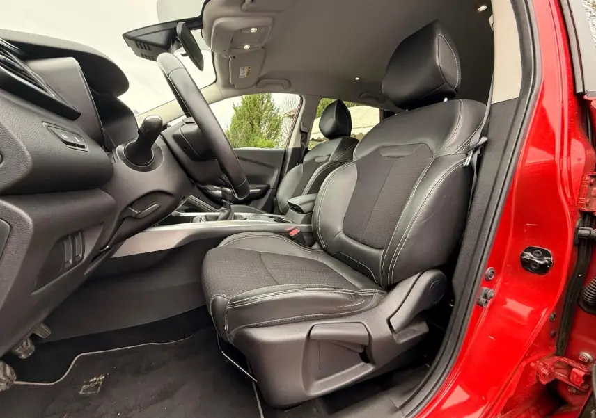 Vue intérieure côté conducteur du Renault Kadjar rouge flamme, mettant en valeur les sièges en cuir noir et la console centrale.