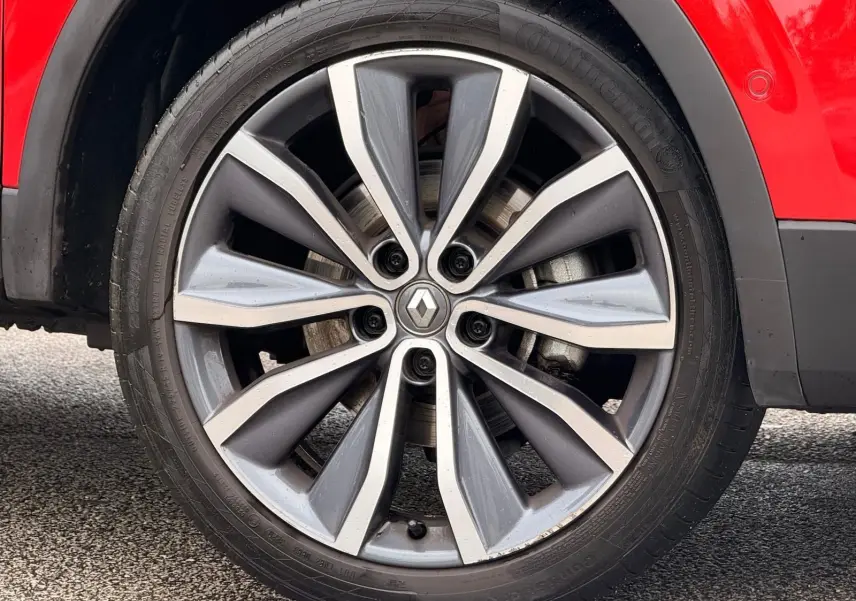 Gros plan sur la roue avant gauche du Renault Kadjar rouge flamme, mettant en valeur la jante alliage bi-ton au design moderne.