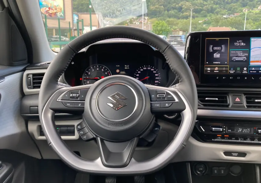 Vue centrée sur le volant cuir multifonctions de la Suzuki Swift 1.2 Dualjet Hybrid Allgrip Pack 2025, tableau de bord et écran tactile visibles.