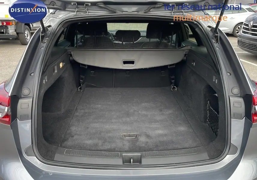Coffre ouvert vu de l'arrière d'une Opel Insignia Sports Tourer gris acier satiné, montrant l'espace de chargement vide.