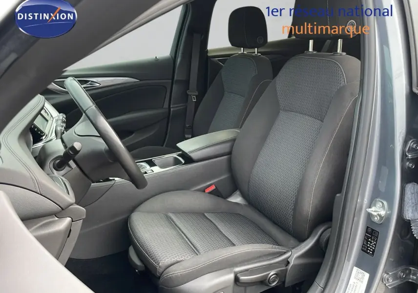 Vue intérieure côté conducteur de l’Opel Insignia Sports Tourer 2021, sièges tissu gris et portière gris acier satiné ouverte.