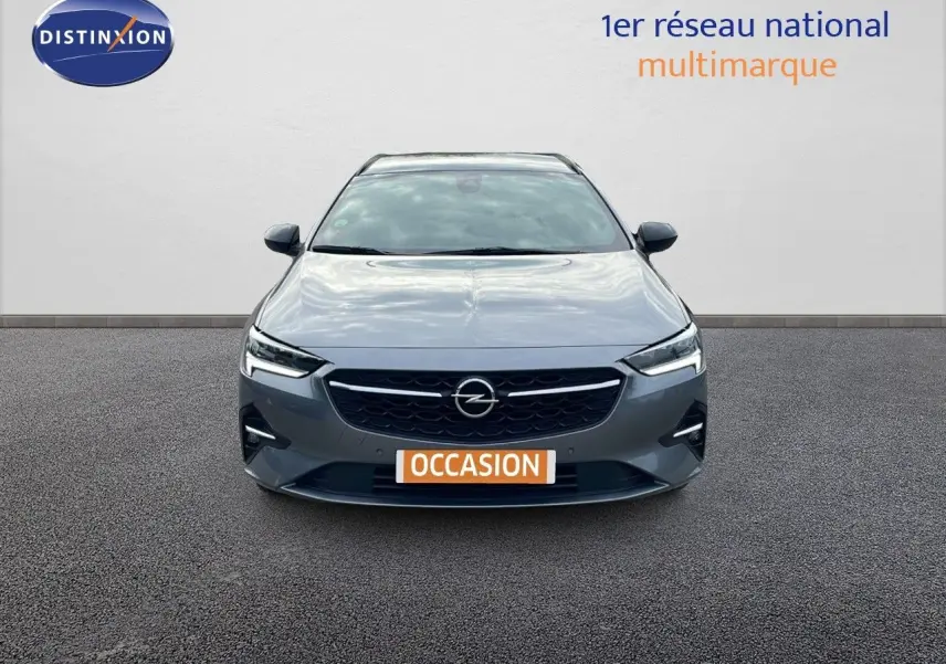 Vue frontale d'une Opel Insignia Sports Tourer gris acier satiné avec calandre noire et phares LED allumés.