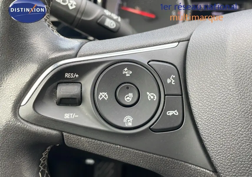 Gros plan sur les commandes au volant noir de l'Opel Insignia Sports Tourer, mettant en valeur les boutons de régulateur et assistance.