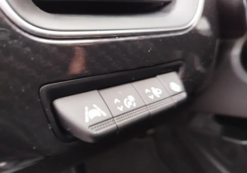 Gros plan sur les boutons de contrôle d’assistance à la conduite du tableau de bord d’un Renault Arkana bleu Zanzibar.