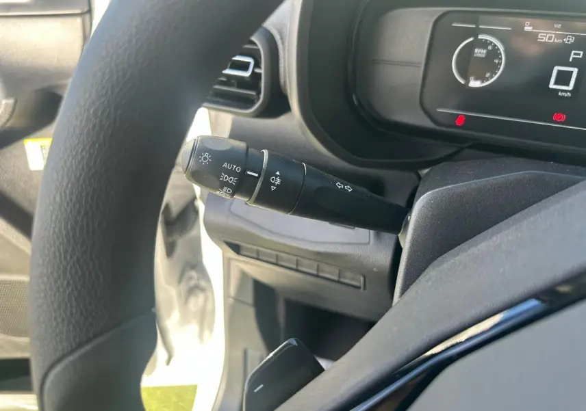 Vue rapprochée du tableau de bord numérique du Citroën Berlingo blanc, affichant la consommation et la vitesse.