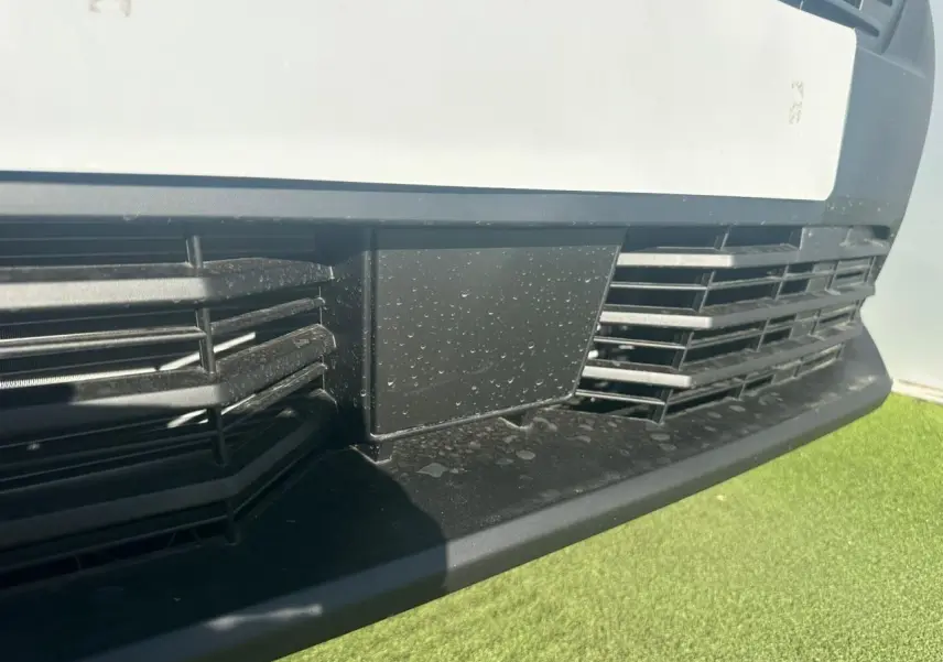 Gros plan sur la calandre noire et la partie basse blanche du Citroën Berlingo III van blanc Icy, vue avant rapprochée.