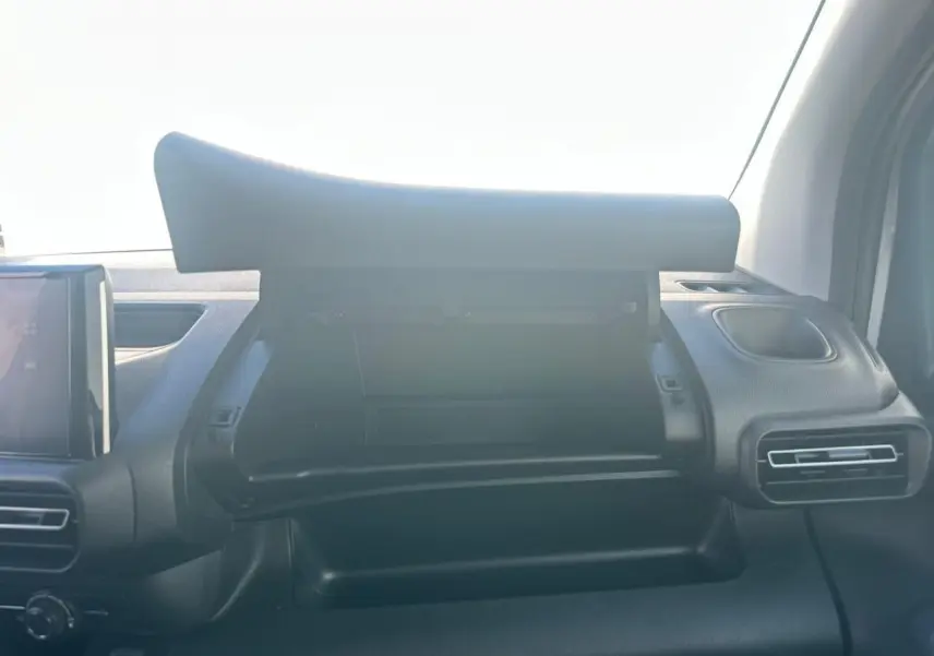 Vue intérieure du tableau de bord du Citroën Berlingo blanc, boîte à gants ouverte avec écran tactile visible à gauche.