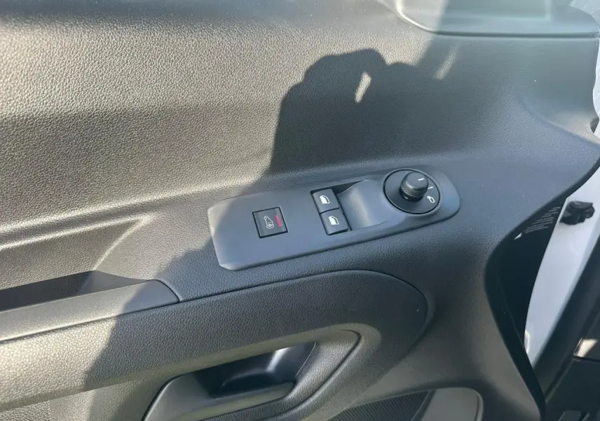 Gros plan sur la porte avant gauche blanche du Citroën Berlingo III, avec commandes électriques des vitres et rétroviseurs.