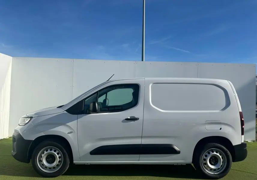 Vue de profil côté gauche d’un utilitaire Citroën Berlingo III blanc Icy avec jantes tôles grises et porte latérale coulissante.
