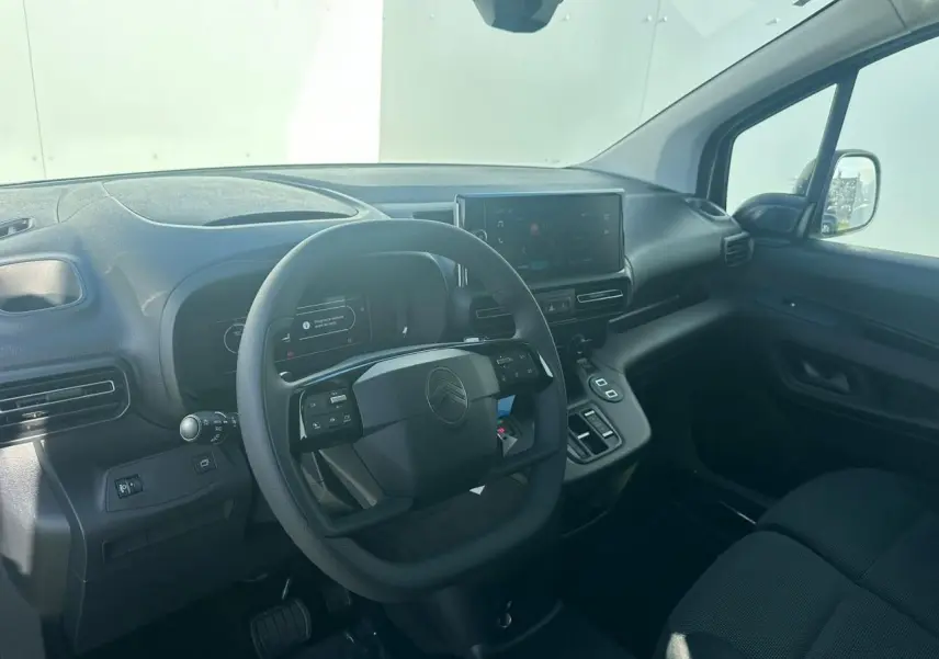 Vue intérieure côté conducteur du Citroën Berlingo blanc Icy, volant multifonctions et écran tactile 10 pouces visible.
