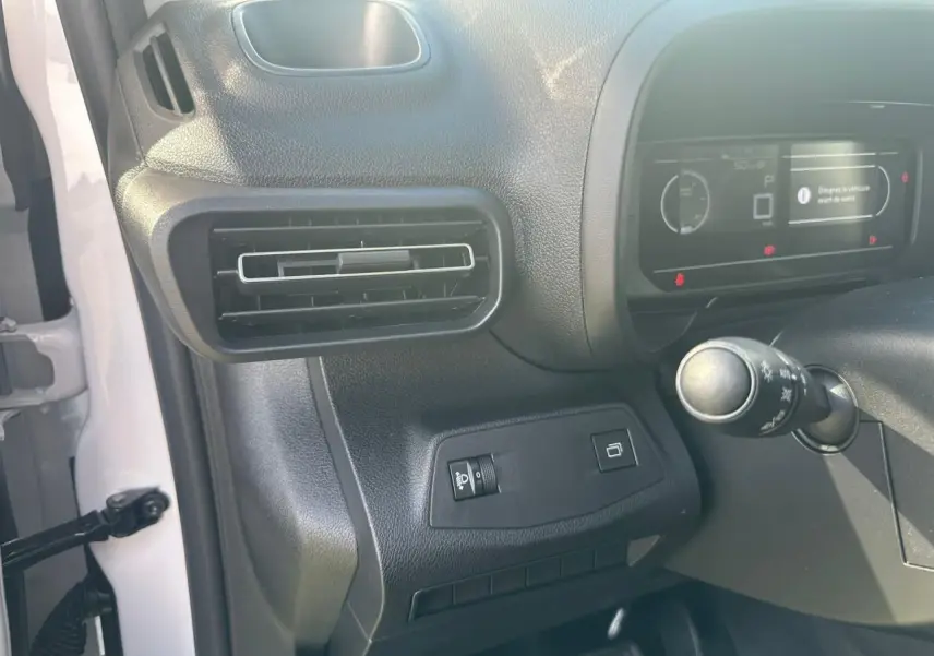 Détail intérieur côté gauche du tableau de bord du Citroën Berlingo blanc, avec aérateur et commandes lumineuses.