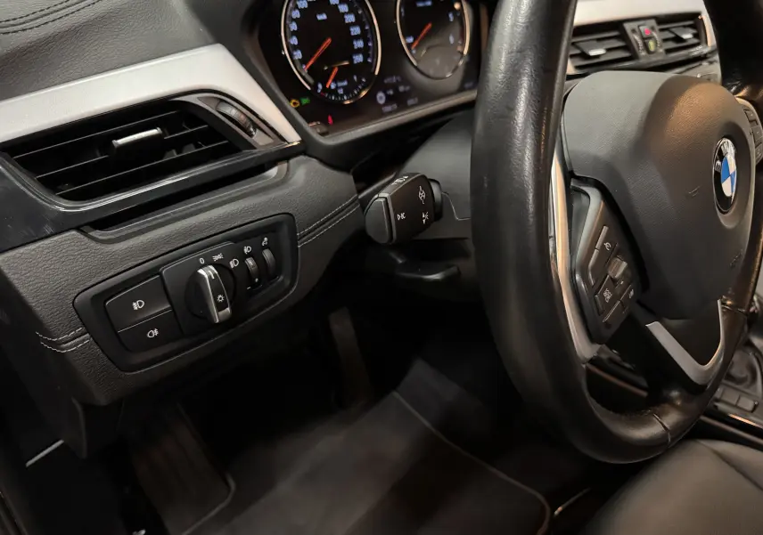 Vue intérieure côté gauche du tableau de bord et volant cuir noir d'une BMW X2 16dA Lounge Plus 2019.