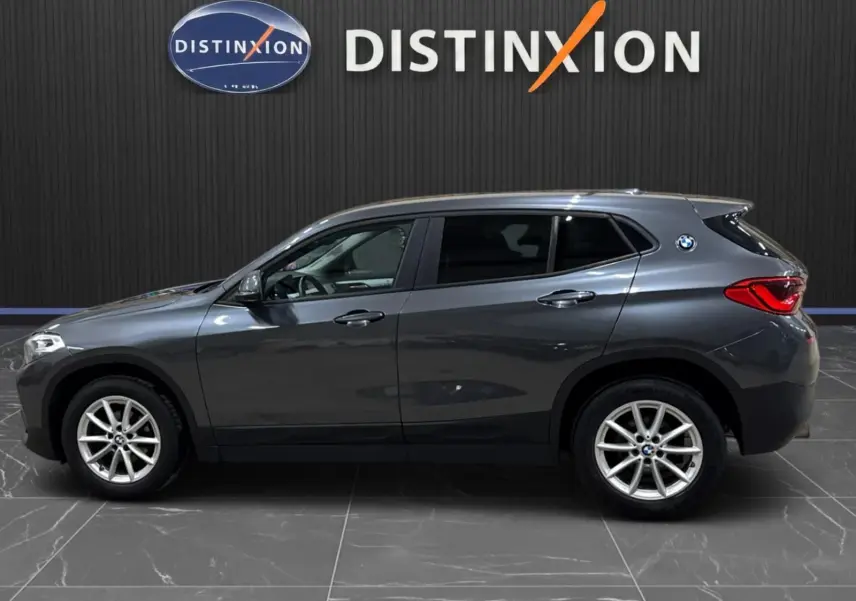 BMW X2 gris minéral métallisé vue de profil côté gauche, vitres arrière surteintées et jantes alliage visibles.