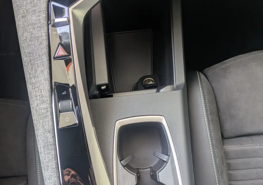 Vue rapprochée de la console centrale du Peugeot 3008 Hybrid 2026, avec sellerie Alcantara et finitions noires élégantes.