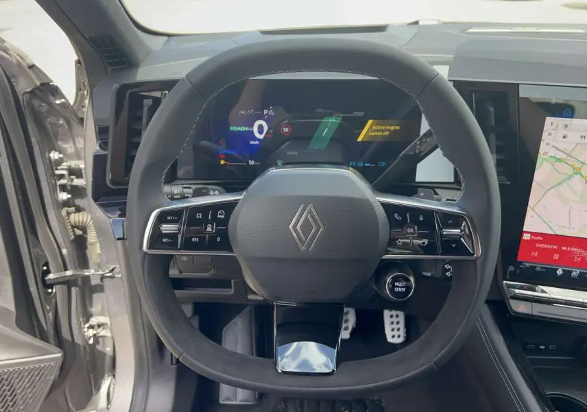 Vue intérieure centrée sur le volant cuir multifonctions du Renault Austral gris schiste avec tableau de bord numérique et écran tactile.
