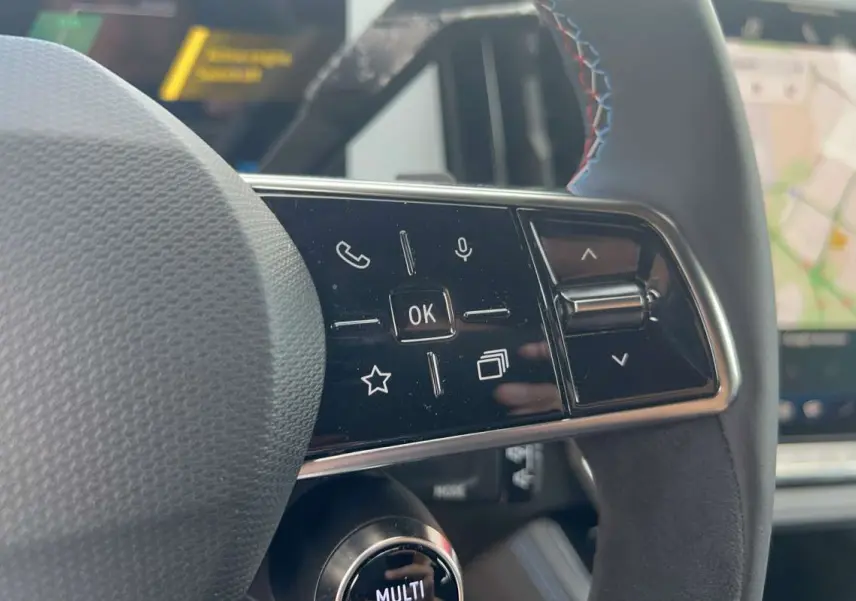 Gros plan sur les commandes multifonctions à droite du volant cuir du Renault Austral 200 Esprit Alpine, avec écran GPS en arrière-plan.