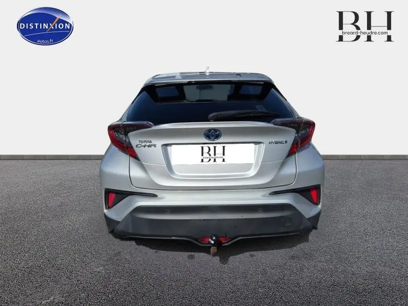 Vue arrière du Toyota C-HR 122h Distinctive gris aluminium avec hayon surteinté et attelage visible.