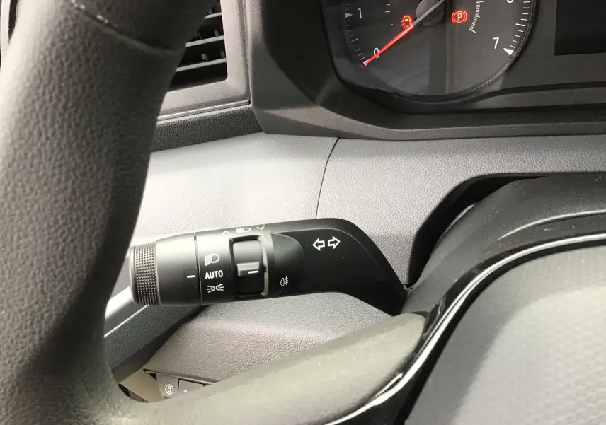 Gros plan sur la commande des clignotants et phares à gauche du volant dans le Renault Master gris urbain 2025.